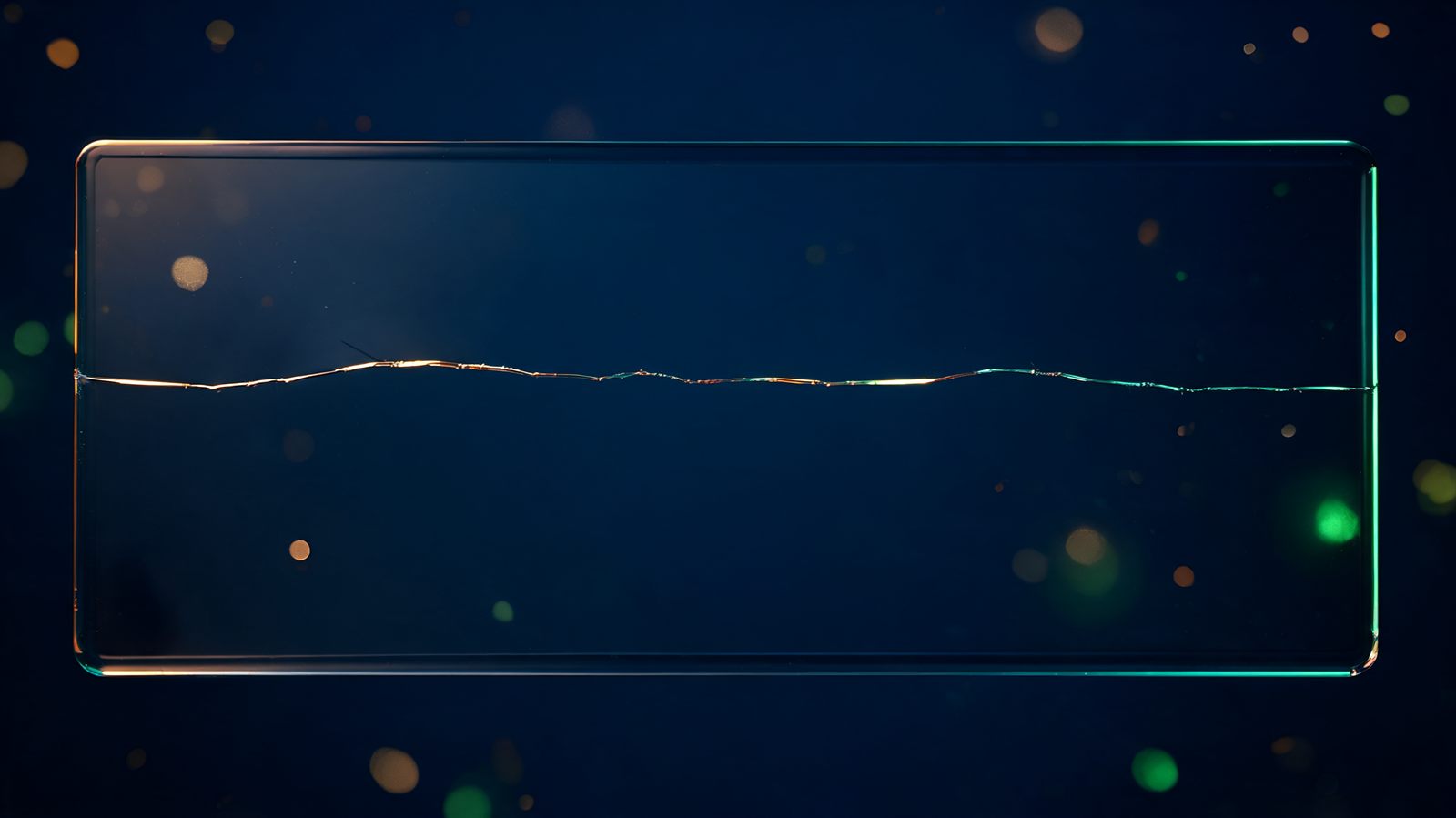 A single clean hairline fracture running across a thick pane of dark glass, light catching along the length of the crack